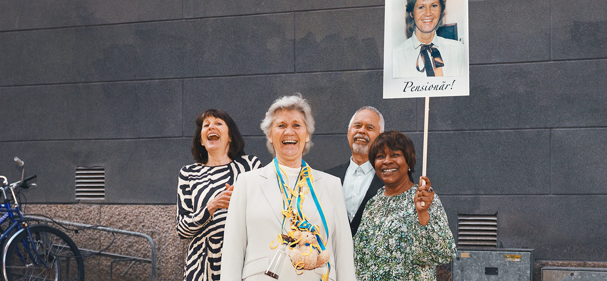 Fyra seniorer "tar pensionen" med plakat, blommor